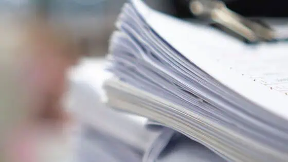 Stacks of printed documents and paperwork on a desk, representing business documentation and administrative processes at RMO Agency.