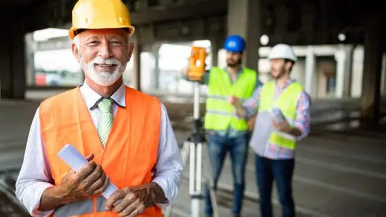 Professional construction site manager inspecting progress, wearing safety gear, overseeing team, under bridge structure, emphasizing construction project management and safety protocols.