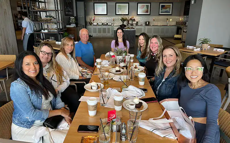 Comfortable team meeting at a modern restaurant, diverse group of professionals enjoying coffee and conversation, emphasizing collaboration and networking in a stylish dining setting.