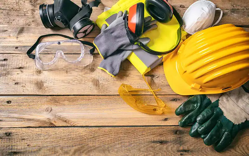 Protective work gear including helmet, gloves, safety goggles, respirator, and ear protection for construction or industrial safety.
