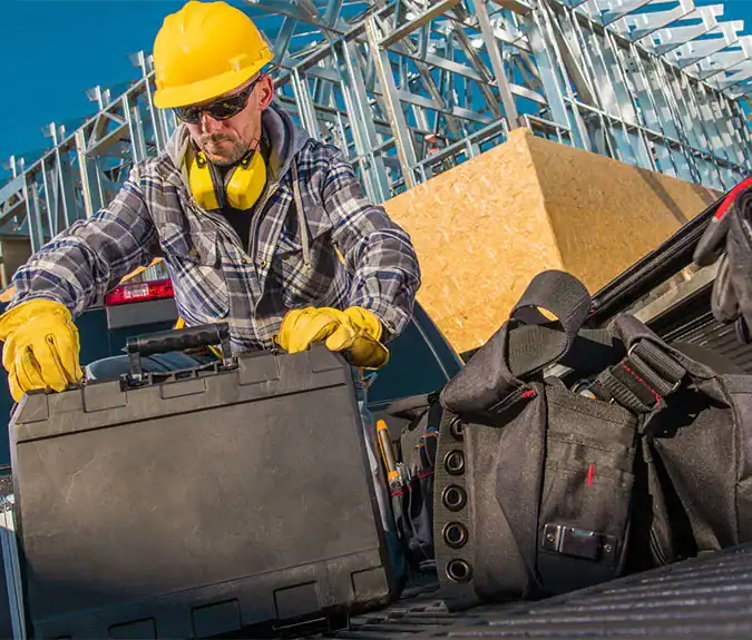 Construction worker with tools at a building site, emphasizing construction services and safety equipment.