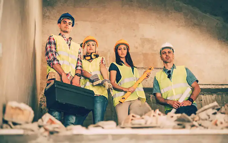 Construction workers inspecting a project site with tools and safety gear, representing professional construction and renovation services.
