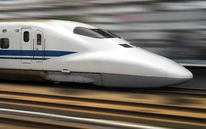 Modern high-speed train speeding along tracks in California, showcasing advanced infrastructure development amid ongoing large projects.